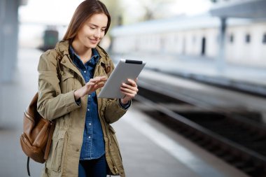 Tren İstasyonu platformu üzerinde duran tablet kullanma sırt çantası olan kadın.
