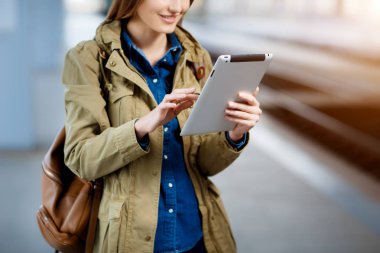 Tren İstasyonu platformu üzerinde duran tablet kullanma sırt çantası olan kadın.