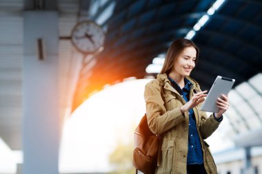 Tren İstasyonu platformu üzerinde duran tablet kullanma sırt çantası olan kadın.