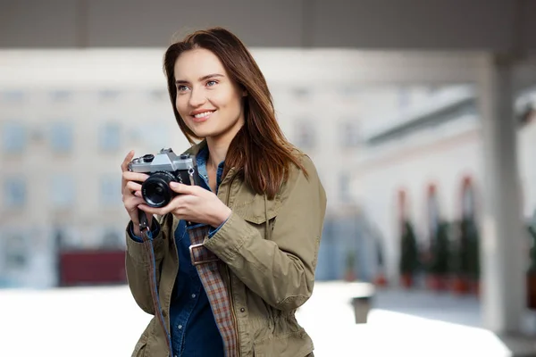 Beautiful young woman using vintage photo camera on the railway station platform. — Stock Photo, Image