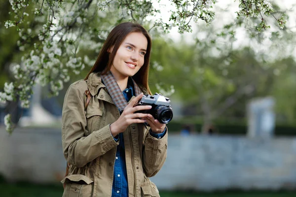 Beautiful young woman using vintage photo camera in the park. — Stock Photo, Image