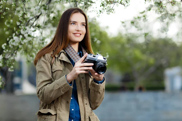 Wanita muda yang cantik menggunakan kamera foto antik di taman . — Stok Foto