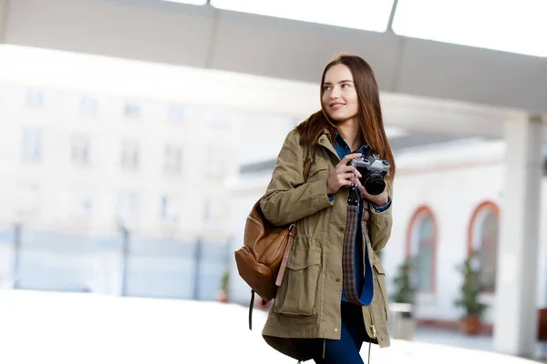 Beautiful young woman using vintage photo camera on the railway station platform. — Stock Photo, Image