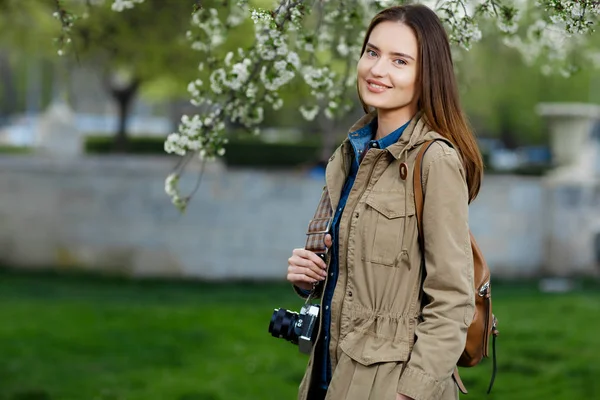 Young beautiful woman walking in the park. Traveler with vintage camera. — Stock Photo, Image