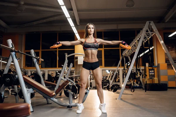 Athlétique jeune femme entraîne ses épaules avec des plaques de poids dans la salle de gym , — Photo