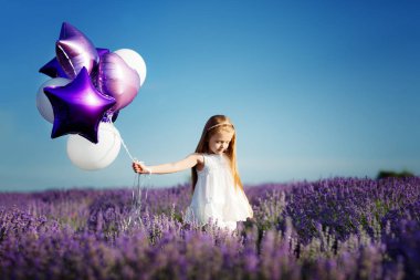 Mor balonlu lavanta alanındaki sevimli küçük kız. Özgürlük kavramı.