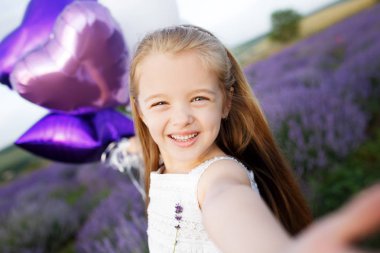 Lavanta alan holding mor çiçekler Buket sevimli küçük kız.