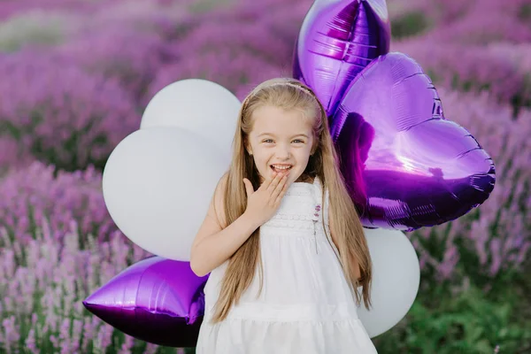 Lavanta alanı mor balon ile mutlu sevimli küçük kız. Özgürlük kavramı.