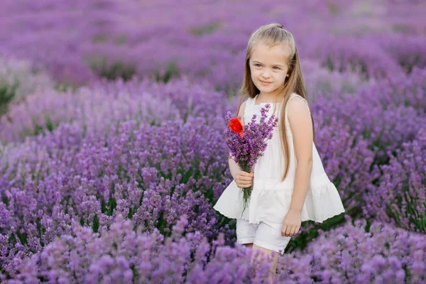 Happy cute little girl in lavender field holding bouquet of purple flowers. — Stock Photo, Image