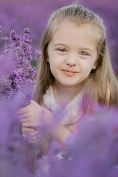 Happy cute little girl in lavender field holding bouquet of purple flowers. — Stock Photo, Image