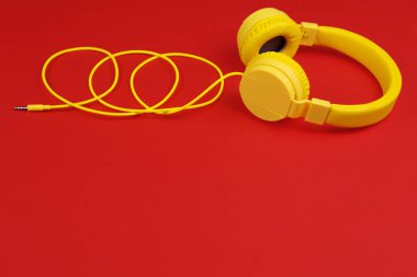 Kırmızı zemin üzerine sarı kulaklıklar. Müzik konsepti.