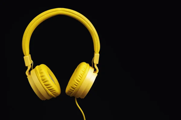 Auriculares amarillos sobre fondo negro oscuro. Concepto musical . —  Fotos de Stock