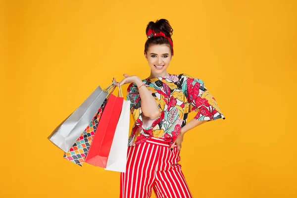 Jovem mulher caucasiana feliz em roupas coloridas casuais segurando sacos e compras sobre fundo laranja . — Fotografia de Stock