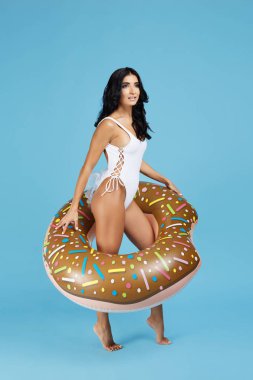 Tam boy görüntü genç ve güzel bir kadının beyaz mayo turuncu zemin üzerine şişme halka ile poz giyinmiş.