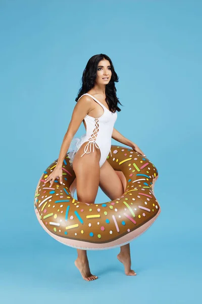 Imagen completa de una hermosa joven vestida con traje de baño blanco posando con anillo inflable sobre el fondo naranja . — Foto de Stock