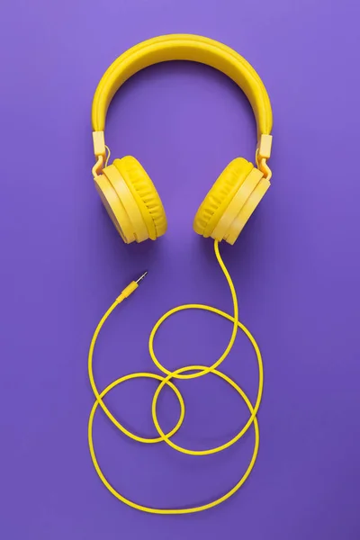 Mor arka planda sarı kulaklıklar. Müzik konsepti.