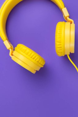 Mor arka planda sarı kulaklıklar. Müzik konsepti.