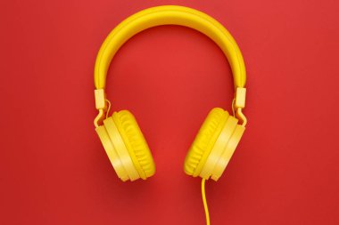 Kırmızı zemin üzerine sarı kulaklıklar. Müzik konsepti.