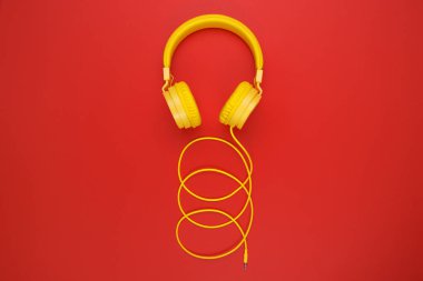 Kırmızı zemin üzerine sarı kulaklıklar. Müzik konsepti.