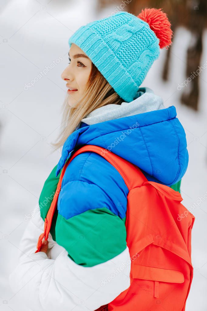 Outdoor portrait of young pretty woman with bagpack posing in the park. Model wearing stylish warm clothes. City lifestyle.