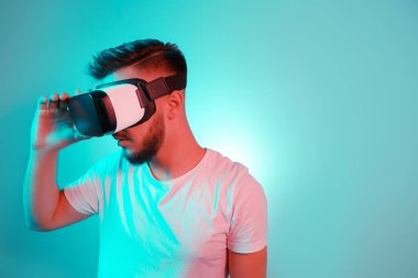 VR kulaklık çalışıyor ve renkli arka plan üzerinde başka bir dünya keşfetmek yakışıklı sakallı adam. VR mezartaşı ile kullanılarak akıllı telefon.