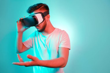 VR kulaklık çalışıyor ve renkli arka plan üzerinde başka bir dünya keşfetmek yakışıklı sakallı adam. VR mezartaşı ile kullanılarak akıllı telefon.