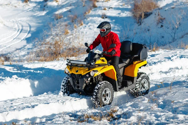 赤の暖かい冬の服と深いホイール トラックと重い雪の中でバギー 4 wd クワッド バイク スタンドに黒ヘルメットの魅力的な若い男。モト冬スポーツ. — ストック写真