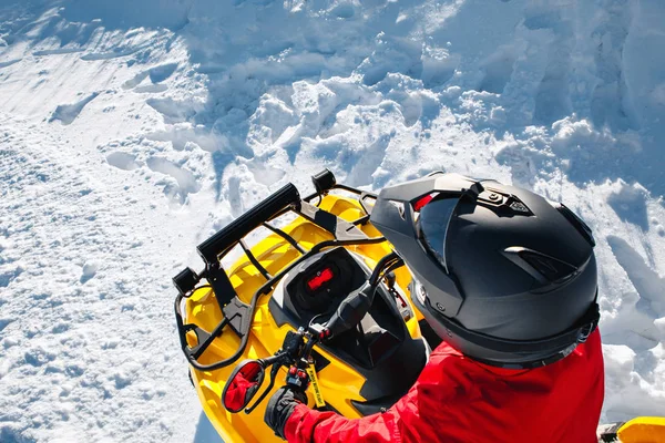 Jovem com roupas vermelhas quentes de inverno e capacete preto no estande de moto quadriciclo ATV 4wd em neve pesada com pista de roda profunda. Moto esportes de inverno. Vista superior . — Fotografia de Stock