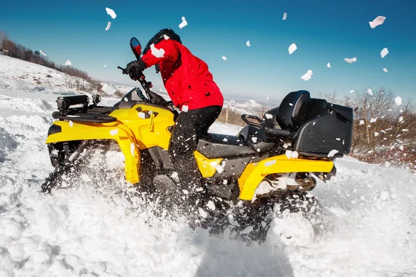 Φωτογραφία: νεαρός extremal οδηγός κόκκινο ζεστά χειμωνιάτικα ρούχα και μαύρο κράνος το αυτοκίνητο του Atv 4wd τετράτροχες stand βαρύ χιόνι με βαθιά τροχό κομμάτι. Extreme moto χειμερινά σπορ. — Φωτογραφία Αρχείου