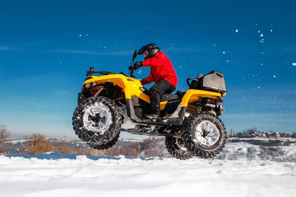赤の暖かい冬の服と黒のヘルメットで若い極値ドライバーの写真は深いホイール トラックで雪の Atv クワッド バイク スタンドが空気にジャンプします 極端なモト冬スポーツ — ストック写真