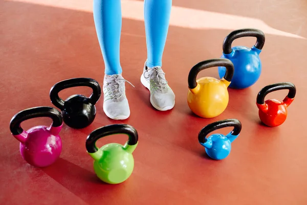Spor salonunda fit genç sarışın kadın bacaklar ve kettlebells yakın çekim fotoğrafı.