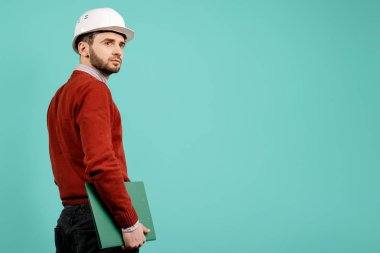 Genç yakışıklı gündelik kıyafeti yeşil Pano mavi arka plan üzerinde tutan mühendisi veya Oluşturucu adam sakallı. Kavramı, Mimarlık ve yenileme.