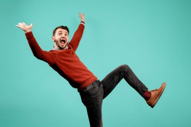 Rahat kıyafeti çekici çılgın sakallı genç adam mavi arka plan üzerinde eğlenin. Başarı ve kazanan kavramı.