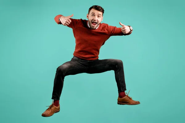 Aantrekkelijke gekke baard jonge man in Casual outfit springen en Toon OK gebaar over cyaan achtergrond. Succes en Winner concept. — Stockfoto