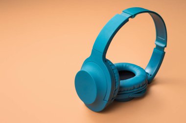 Bej arka planda modern mavi renkli kulaklık fotoğrafı.