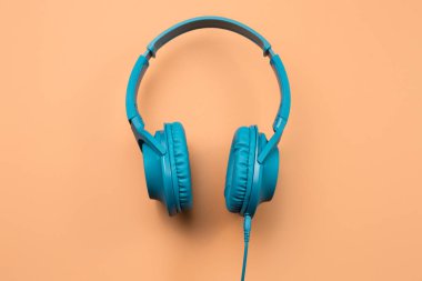 Bej arka planda modern mavi renkli kulaklık fotoğrafı.