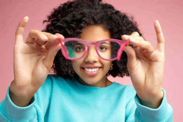 Foto da bela mulher jovem afro-americana olhar através de óculos sobre fundo rosa . — Fotografia de Stock