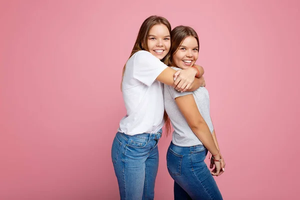 Terang dua saudara kembar muda dengan senyum indah berjalan di atas latar belakang merah muda . — Stok Foto