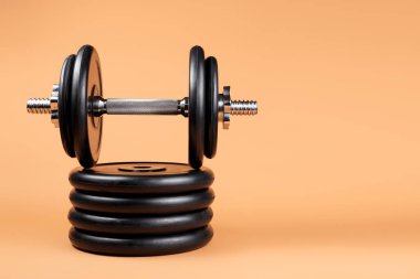 Bej arka plan üzerinde profesyonel halter ve ağırlık plakaları. Krom gümüş saplı siyah metal halter. Spor aletleri. Fitness konsepti.