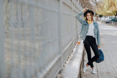 Bir şapka giymiş ve açık havada kameraya bakarak kahverengi saçlı güzel bir gülümseyen hippi kız portresi