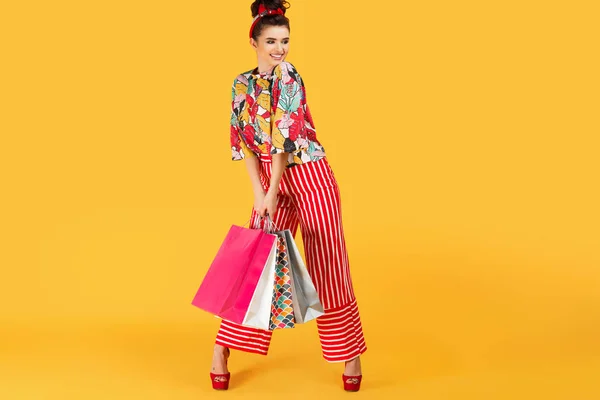 Full lenhts foto av unga lyckliga kaukasiska kvinna i casual färgglada kläder som håller påsar och shopping över orange bakgrund. Shopping och säljkoncept. — Stockfoto