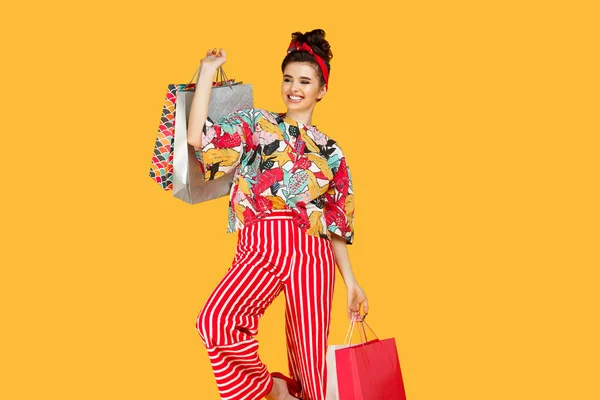 Encantadora jovem caucasiana em roupas coloridas casuais segurando sacos e compras sobre fundo laranja. Conceito de compras e vendas . — Fotografia de Stock