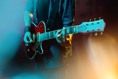Neon ışıklar kırmızı gitar ile hipster adam yakın çekim fotoğraf. Rock müzisyeni elektrik gitar çalıyor.