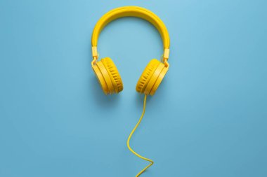 Mavi arka planda sarı kulaklıklar. Müzik konsepti.