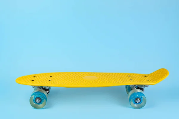 Foto skateboard giallo o pennyboard su sfondo blu. Copia spazio . — Foto Stock