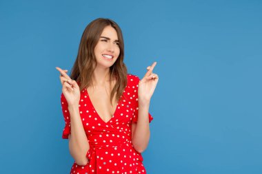 Mavi arka plan üzerinde umut geçti parmakları ile el ele bakarak kırmızı elbiseli parlak gülümseme ile mutlu kadın.