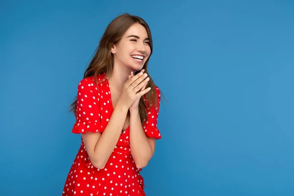 Izgatott fiatal nő, világos mosoly piros ruhában látszó el több mint kék háttér. — Stock Fotó