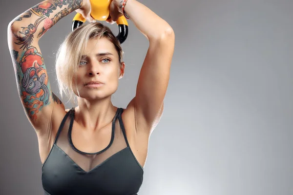 Fit young blonde woman workout in the studio with kettlebell. — Stock Photo, Image