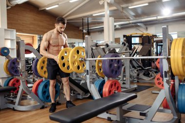Güçlü atletik genç adam vücut geliştirme fitness modeli spor salonundaki halterlere ağırlık koydu..