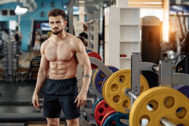 Çekici kas atletik genç adam vücut geliştirmeci fitness modeli spor salonunda egzersizleri sonra poz.